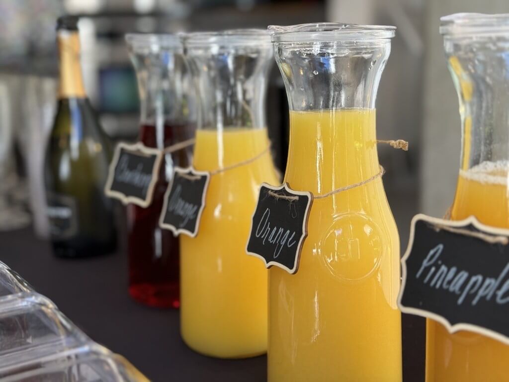 Labelled juice carafes at the RISE Thrive mimosa bar during a resident brunch at The Lofts on Post Oak